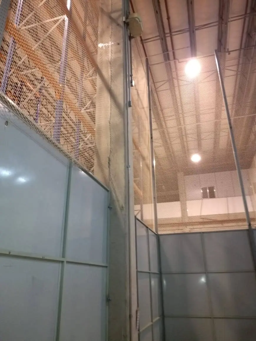 Fechamento vertical superior com rede de proteção acima de divisória industrial em centro de distribuição